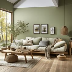 a living room with green walls and wooden flooring is pictured in this image, there are pictures on the wall above the couch