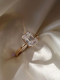 an engagement ring is sitting on a white cloth