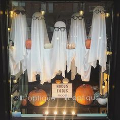 a display case filled with white ghost costumes and pumpkins