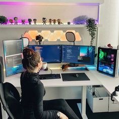 a woman sitting at a desk in front of two computer monitors