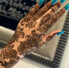 a woman's hand with blue fingernails and henna on her hands, in front of a mirror