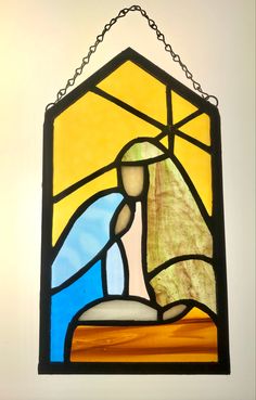 a stained glass window hanging from the side of a wall with a person in it