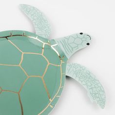 a paper plate with a green turtle on it's back and gold trim around its neck