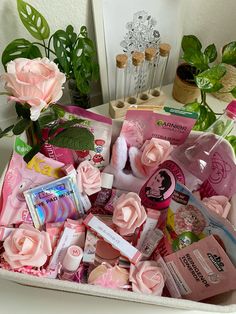 a white basket filled with lots of different items next to a pink rose and potted plant