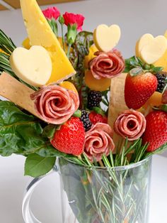 a glass vase filled with fruit and veggies on top of a white table