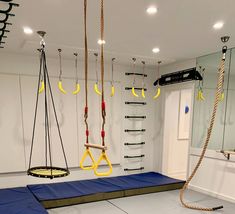 an indoor gym with swings and ropes hanging from the ceiling, mirrors on the wall