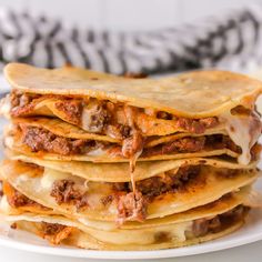 a stack of quesadillas stacked on top of each other with meat and cheese