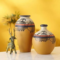 two brown vases sitting on top of a table next to a small figurine