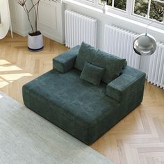 a green couch sitting on top of a hard wood floor next to a radiator