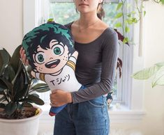 a woman holding a stuffed doll next to a potted plant