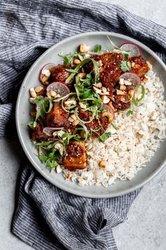 a white plate topped with rice, meat and veggies next to a blue towel