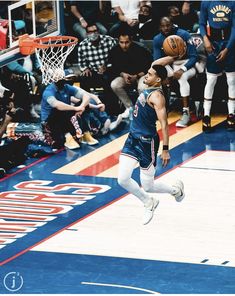 a basketball player is jumping up to dunk the ball in front of an audience