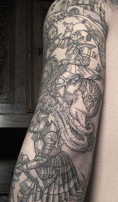 a man's arm with tattoos on it and an image of a demon in the background