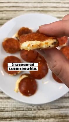 a white plate topped with mini pizzas on top of a wooden table next to a person's hand