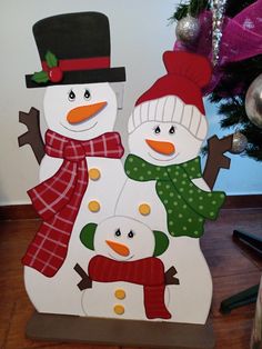 two snowmen standing next to each other in front of a christmas tree