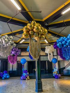 balloons and streamers are hanging from the ceiling in an open space with a chandelier