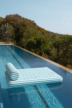 an inflatable mattress sitting on the edge of a swimming pool with trees in the background