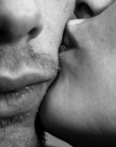 a man and woman kissing each other with their noses close to one another, black and white photograph