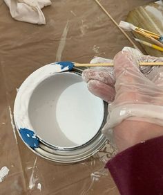 a person is painting a white bowl with blue paint