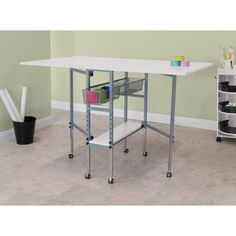 a white table sitting on top of a floor next to a shelf filled with craft supplies