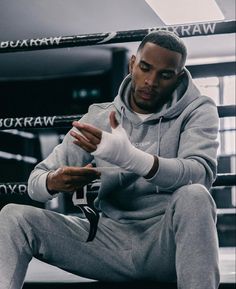 a man sitting on top of a bench wearing a gray sweat suit and white gloves