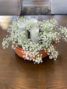 two candles are sitting in a flower pot on a table with baby's breath