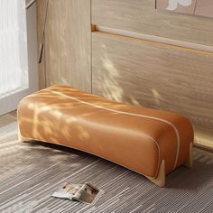 an orange bench sitting on top of a wooden floor next to a window with blinds