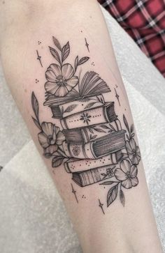 a tattoo on the arm of a woman with books and flowers