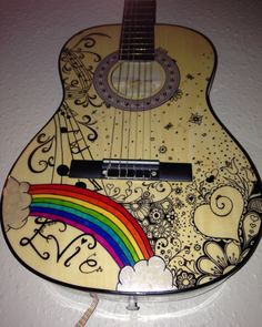 a wooden guitar with a rainbow painted on it