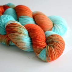 two skeins of orange and blue yarn sitting on top of a white surface