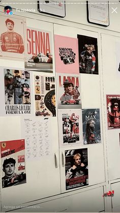 a refrigerator covered in posters and magnets next to a wall with writing on it