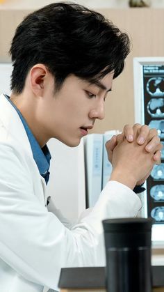 a male in a white coat is praying