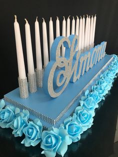 a blue birthday cake with candles and flowers on the side that says 8 / 6