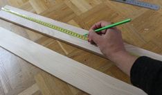 a person is measuring wood with a green ruler on the floor next to some rulers