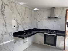 an empty kitchen with black counter tops and white marble backsplashes on the walls