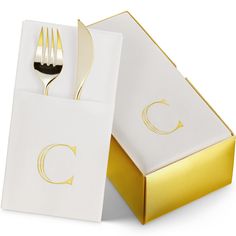 a fork and napkin in a box with a gold foil logo on the side,