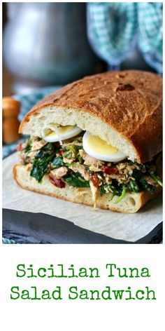 there is a sandwich with an egg on it and the words sicilian tuna salad sandwich