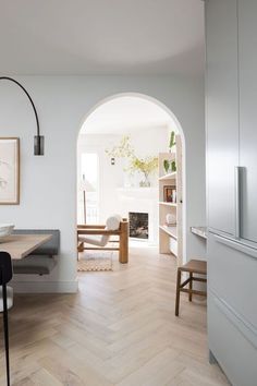 an arched doorway leads to a dining room with white walls and wood flooring, along with modern furniture