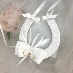 a white ribbon and ring holder with flowers in the background on a veiled surface