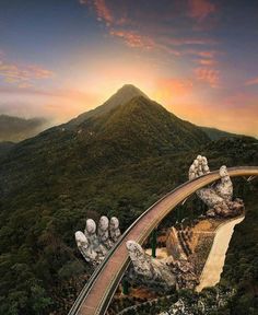 an aerial view of a bridge with mountains in the background and trees on both sides