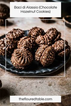 chocolate cookies on a black plate with spoons in the background and more cookies scattered around