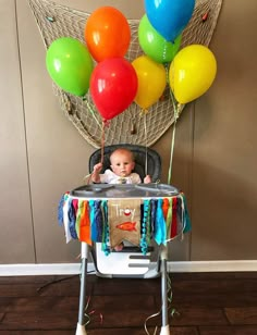 a baby in a high chair with balloons