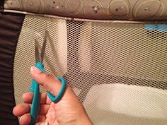 a person holding scissors in their hand near a crib with a mattress behind them