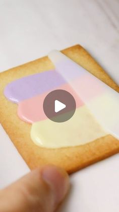 a hand holding a cookie with white icing on it and a video playing in the background