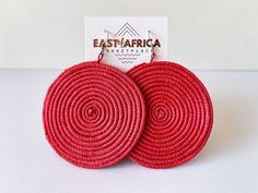 Hand woven grass earrings in RED made exclusively for us in East Africa and are fair trade and directly sourced from artisans in Arusha, Tanzania. We trade regularly with a small collective of artisans, to ensure long term, sustainable employment.   Lightweight and vibrant. 6cm diameter. Each pair of earrings come in a handmade African Wax Print gift bag. We have added high quality, nickel free earring hooks. Please note that due to handmade nature of this item, it may have irregularities. Do not wet. Will fade if stored in direct sunlight. Colour may appear slightly different online. Thanks for your partnership with us with artisans in East Africa. Arusha, African Earrings, Nickel Free Earrings, Handmade African, African Wax Print, Wax Print, Print Gifts, Handmade Natural, Jewelry Earrings Dangle