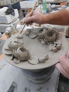 a person is working with clay flowers on a plate in the process of being made