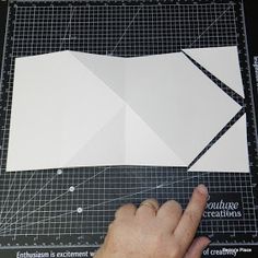 someone is cutting out an origami piece on a table with black and white paper