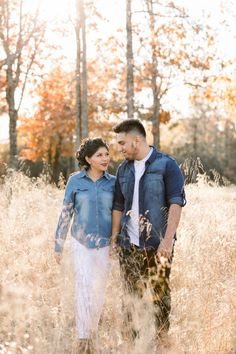 a man and woman standing in tall grass