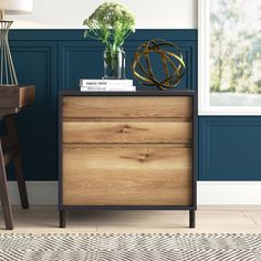 a wooden dresser with two drawers and a lamp on top of it next to a chair