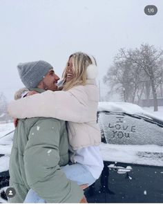 two women hugging each other in front of a car on a snowy day with trees and snow